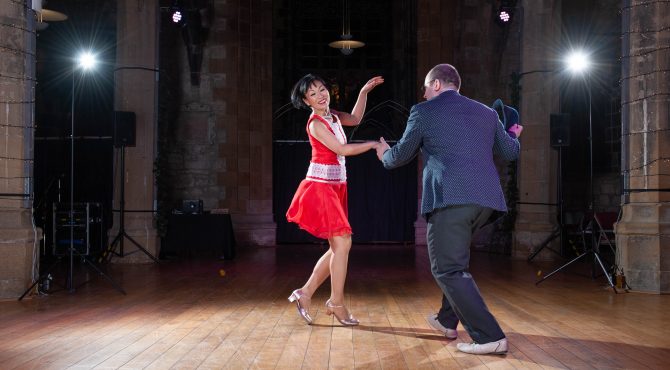 Joo-Lee dancing with Andy at the Lindy Jazz Snow Ball. She is wearing a red dress and is smiling.